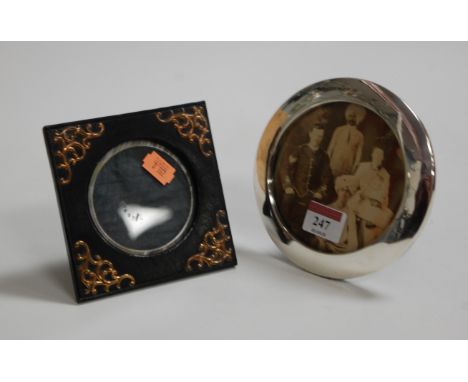 A silver circular easel photograph frame, undecorated, dia.14cm; together with an ebonised and brass mounted easel photograph