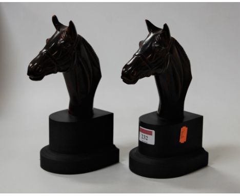 A pair of book-ends, each modelled as glazed ceramic horses heads on plinths, h.23cm