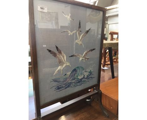 A needlework fire screen depicting gulls over breaking waves. 