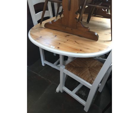 A pine and white painted oval dining table and four rush seated ladder back chairs. 