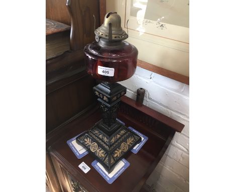 A Victorian oil lamp with cranberry glass reservoir and cast iron base moulded with Aesthetic style detail, height 44cm (incl