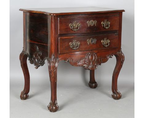 An 18th century rosewood commode, possibly Colonial French, the serpentine top above two drawers, raised on carved cabriole l