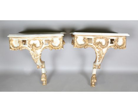 A pair of modern Rococo style white painted and gilt carved wooden console tables with shaped marble tops, height 60cm, width
