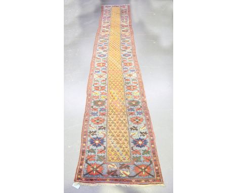 A Kurdish runner, late 19th/early 20th century, the mustard yellow field with overall stylized plants, within a shaded blue p
