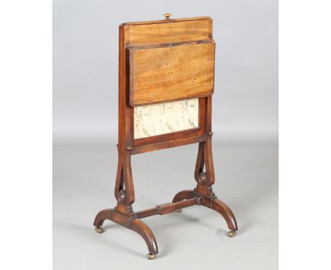 An early Victorian mahogany firescreen, the lift-up panel inset with a floral silkwork above a hinged flap and a pair of carv