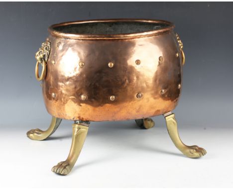 An early 20th century Continental copper and brass studded oval log bin with lion mask ring handles and claw feet, height 40c