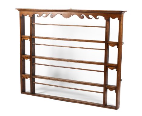 A Victorian oak four tier hanging plate rack, with scroll carved frieze and details, each shelf between two upright supports,