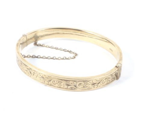 A 9ct gold bangle with engraved decoration and a safety chain, 11.9g
