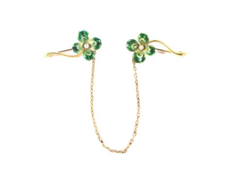 A yellow metal floral enamel twin brooch, in the form of flowers attached with a saftey chain, stamped 14k