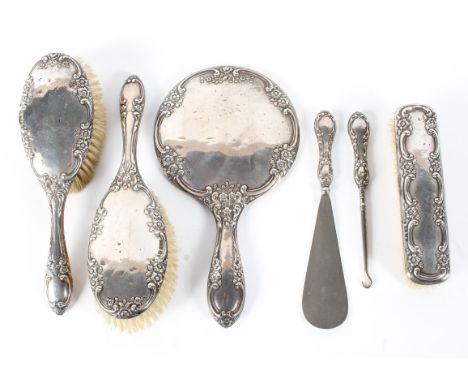 A silver backed four piece dressing table set, including brushes, hand mirror and shoe horn, also a silver handled button hoo