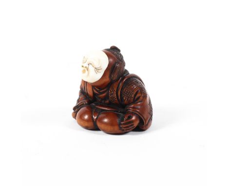 A 19th century wood netsuke of a man in a patterned robe crouching and wearing an ivory usofuki (whistling) mask, signed poss