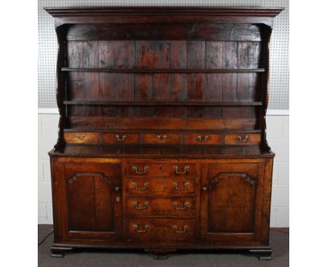 A fine late 18th century closed oak dresser, with three open plate racks above four drawers with brass drop handles, the base