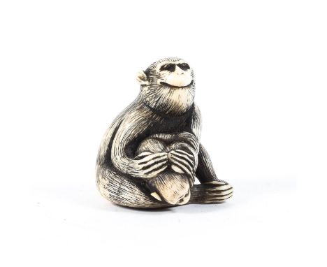 A Japanese Meiji period ivory netsuke of seated monkey holding a baby monkey searching for the fruit hidden beneath the large