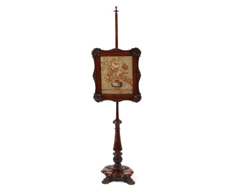 A Victorian carved mahogany pole screen with tapestry screen, the scroll shaped adjustable screen carved with palmettes, on t