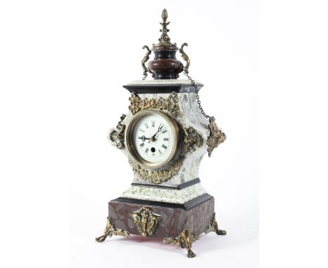 A late 19th century French brass, marble and stone mounted mantel clock, with urn finial suspending chains attached to masks,