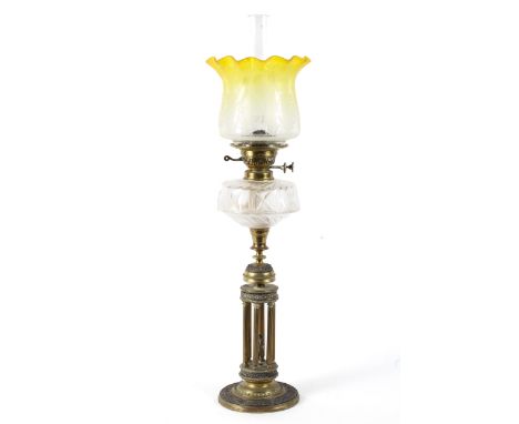 A late 19th century brass column oil lamp, with etched yellow tinted shade and funnel above six reeded columns around a figur