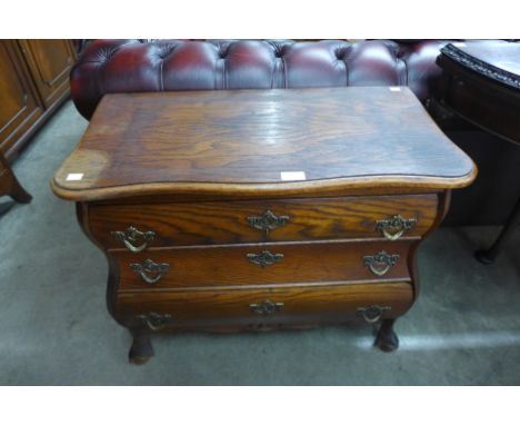 A Dutch oak three drawer bombe shaped petit commode 