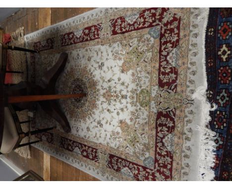 A Persian cream ground Tabriz rug, having central floral medallion on a foliate and floral ground, multi-bordered and fringed