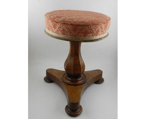 An early 20th century walnut piano stool, with round stuffover upholstered seat raised on baluster column, tripod base, suppo