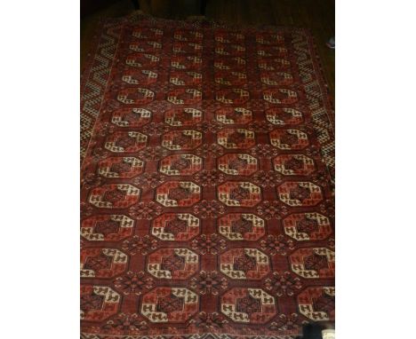 A red ground Turkoman carpet, having four rows of elephant pad medallions to centre, multi-bordered and fringed, L.270cm, W.2