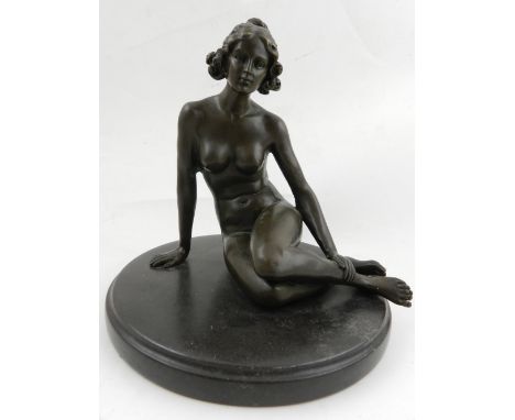 A bronze sculpture of a seated nude, raised on a circular base.