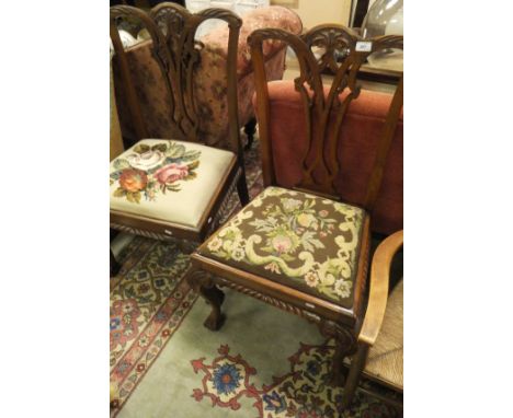A pair of Chippendale style dining chairs with carved splat backs above needlework decorated drop-in seats, above carved cabr