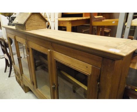 A modern pine dresser unit with four glazed doors above a central recess flanked by two banks of four drawers, a shoe shine b