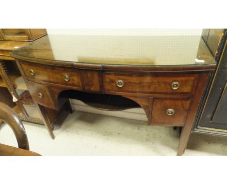 An early 20th Century mahogany bow front sideboard, the plain top above four drawers with brass ring handles above an underti