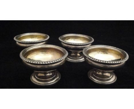 A set of four George III silver salts of circular pedestal form with gadrooned rims and raised on circular stepped bases (by 