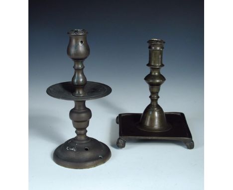 Two 17th/18th century brass candlesticks, the turned column of the English stick on a dished square base with four 'paw' feet