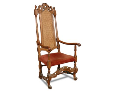 A William & Mary walnut elbow dining chair, with carved and pierced crest rail, cane back and later upholstered seat, on scro