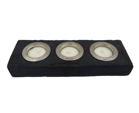 Three modern silver tealight holders, hallmarked Laurence R Watson & Co, Birmingham 2012, housed within rectangular slate dis