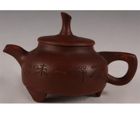 An Oriental red glazed TEAPOT of shallow form with incised flower sprig and cyphers to the body 18cm across 11cm high