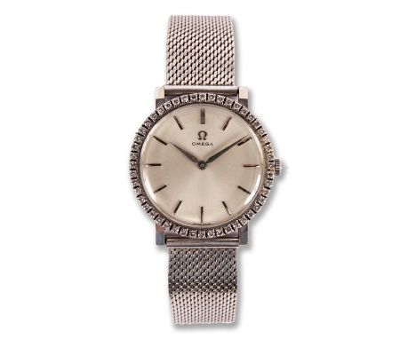 A gentleman's vintage 18 carat white gold Omega WRISTWATCH with diamond set bezel and silvered dial with baton markers 32mm d