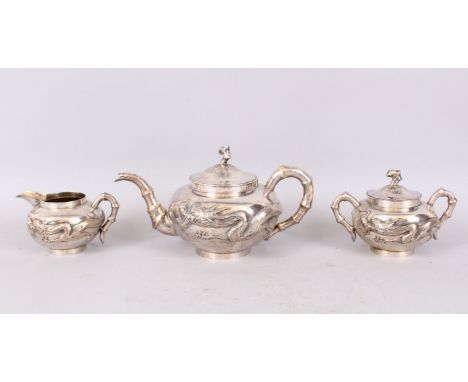 A GOOD CHINESE SILVER THREE PIECE TEA SET, decorated with dragon in relief, comprising teapot and cover, sugar basin and cove