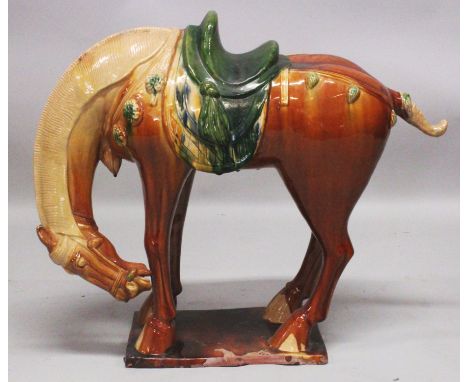 A LARGE CHINESE TANG STYLE GLAZED CERAMIC FIGURE OF A STANDING HORSE, applied with green and ochre glazes, 25.5in long &amp; 
