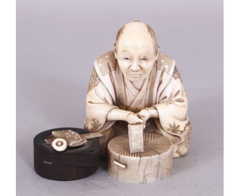 A SIGNED JAPANESE MEIJI PERIOD WOOD &amp; IVORY OKIMONO OF A SEATED ARTISAN, holding a chisel above a circular block, the bas