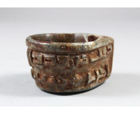 A SMALL EARLY ISLAMIC CARVED STONE OIL LAMP, the sides carved with calligraphy, 8cm x 7cm, 4cm deep.