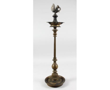 A TALL 19TH CENTURY SOUTH INDIAN BRASS CANDLESTICK with bird terminal and circular base.
