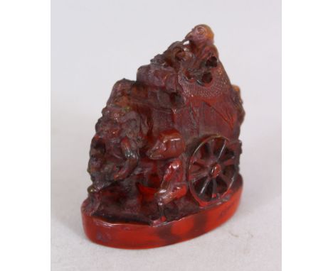 A 20TH CENTURY JAPANESE AMBER STYLE NETSUKE, carved in the form of a man with a cart accompanied by oni, tengu and a monkey, 