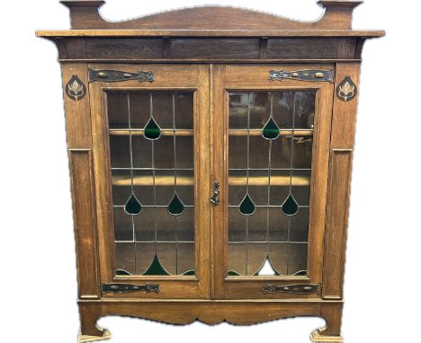 Arts and crafts bookcase, the back rail above two stained glass glazed doors opening to shelved interior, raised on bracket f