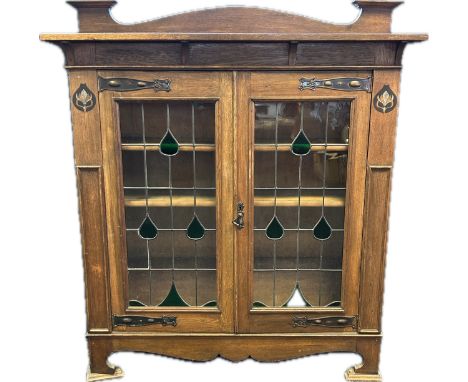 Arts and crafts bookcase, the back rail above two stained glass glazed doors opening to shelved interior, raised on bracket f