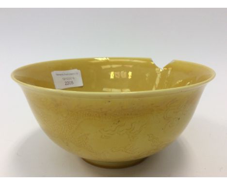 A Chinese bowl, probably Kangxi mark and period, iridescent yellow glaze over a sgraffito design of a dragon chasing a flamin
