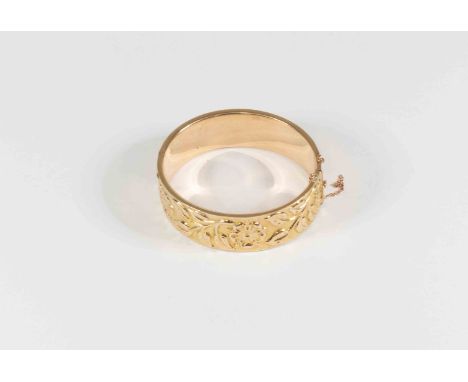 A 9ct gold bracelet, hollow form with embossed foliate detail, approx width 19mm, internal diameter approx 58mm, with tongue 