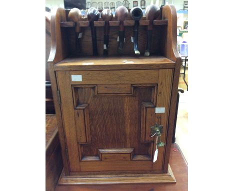 An early 20th Century Oak smokers companion, top pipe rail above, single door with drop handle, interior with shelf (six pipe