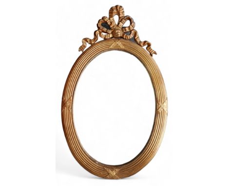 An oval gilt modern mirror, with ribbon top detailing. 