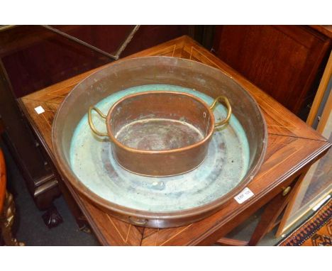 A shallow circular copper planter with a smaller twin handled example