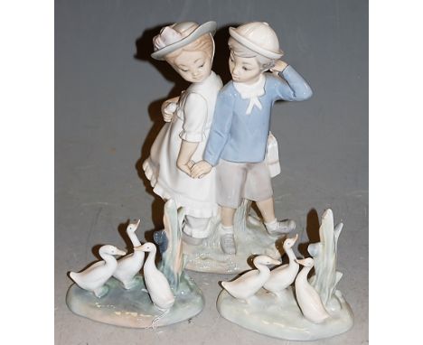 A Lladro figure group of a boy and girl in standing pose holding hands, printed mark verso, height 26cm, together with a pair