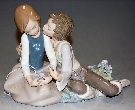 A Lladro figure group boy & girl in seated post holding flowers, printed mark verso, height 16cmLosses to flowers.