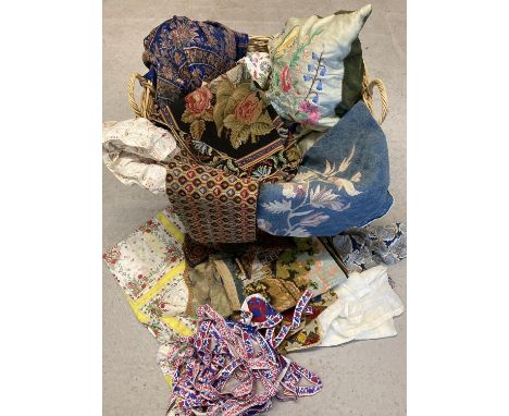 A large 2 handled wicker basket containing a quantity of vintage materials, tapestry panels and braiding in varying sizes and